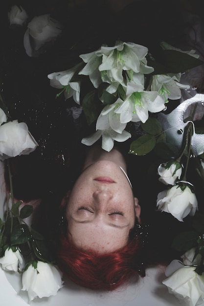 Photo relaxing, teen submerged in water with white roses, romance scene
