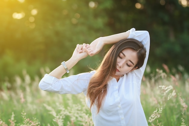 Relaxing woman on green grass meadow in the summer sunset 