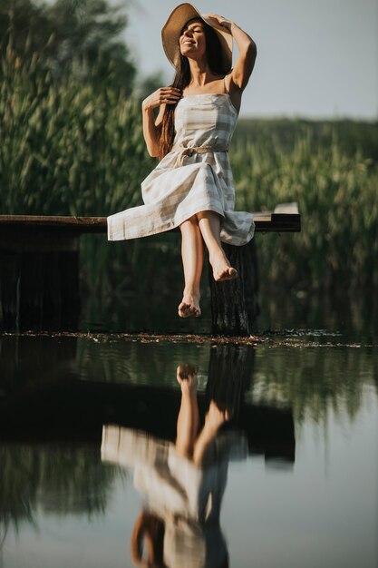 평온한 호수에서 목재 부두에서 편안한 젊은 여자