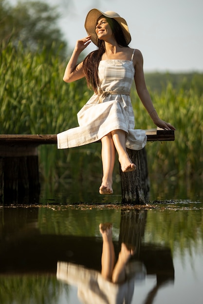 Relaxing young woman on wooden pier at the calm lake