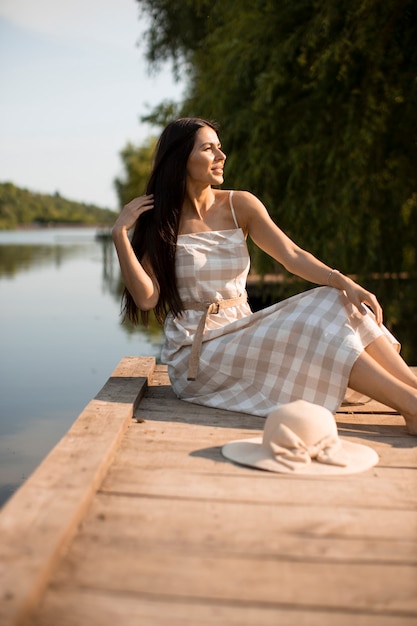 Relaxing young woman on wooden pier at the calm lake