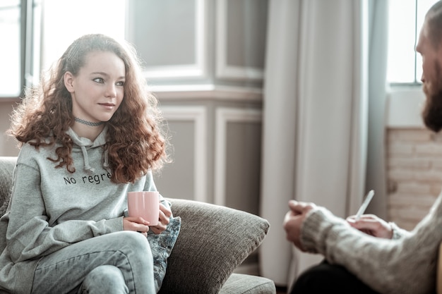 Relieved at counseling. Pleasant appealing curly teenager feeling relieved during counseling