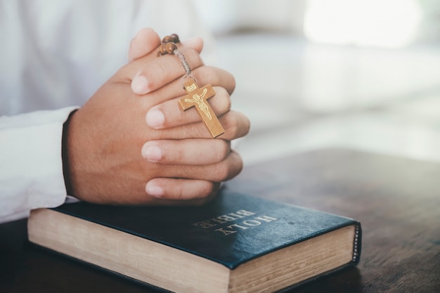 Religie, christendom, bidden. Man bidden, handen samen gevouwen op haar Bijbel.