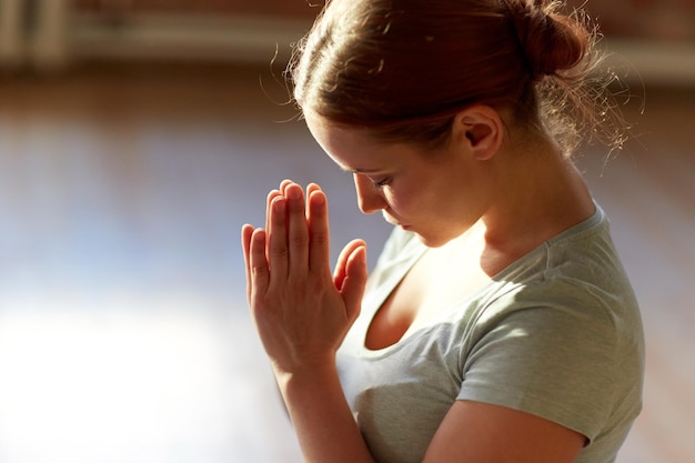 religie, geloof en mensenconcept - close-up van vrouw die mediteert in yogastudio