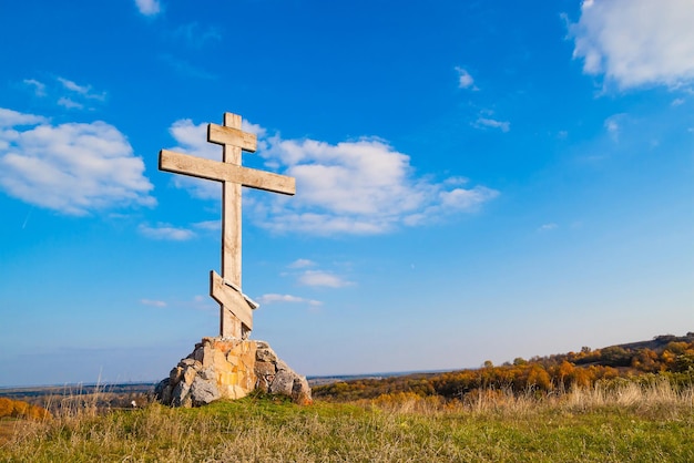 Religieus houten kruis op een heuvel tegen de blauwe lucht