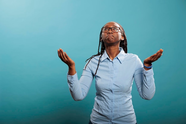 Religieuze en spirituele jongere die bidt voor een betere en vergevingsgezinde wereld. trouwe afro-amerikaanse vrouw met handpalmen naar de hemel gericht, smekend en smekend om vergeving van haar zonden.