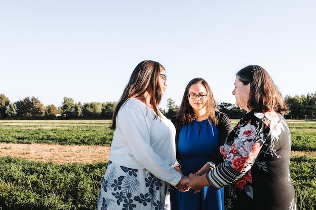 Religieuze familie grootmoeder moeder en dochter bidden in het veld op een zonnige dag middag