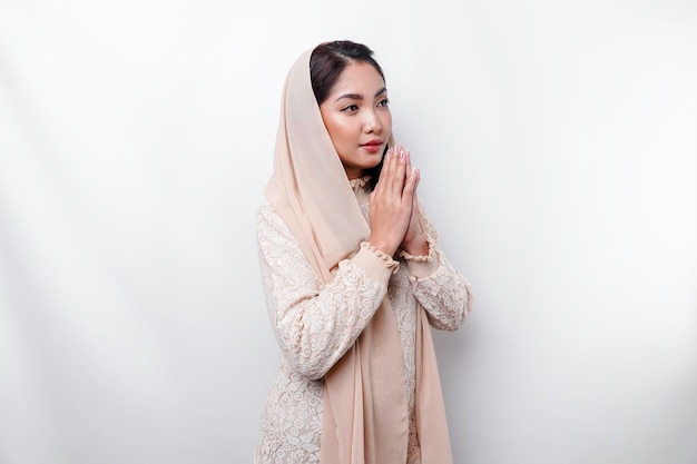 Религиозная красивая азиатская мусульманка в платке молится Богу