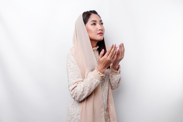 Религиозная красивая азиатская мусульманка в платке молится Богу