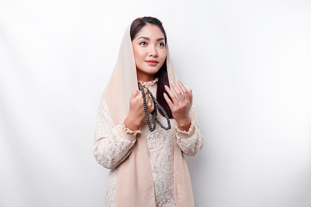 Religious beautiful Asian Muslim girl wearing a headscarf praying to God