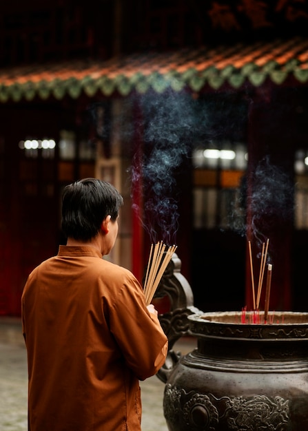 燃える線香を持つ寺院の宗教的な男