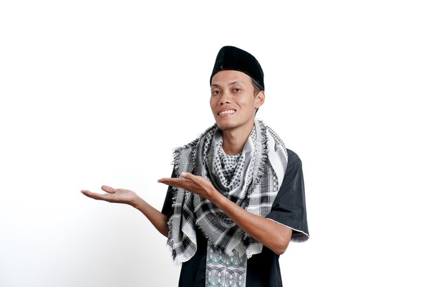 Religious muslim asian man wearing turban muslim dress and cap pointing to the side of empty space Isolated on white background