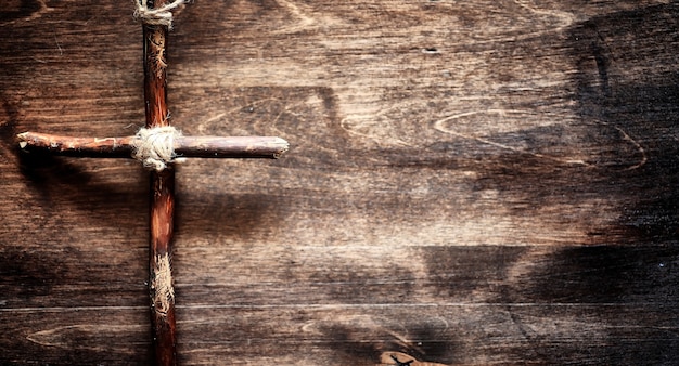 Religious old book on a wooden table. A religious cross tied with a rope and burlap next to bible. Worship, sins and prayer.