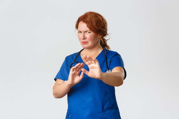 Reluctant and displeased redhead female doctor asking to stay away