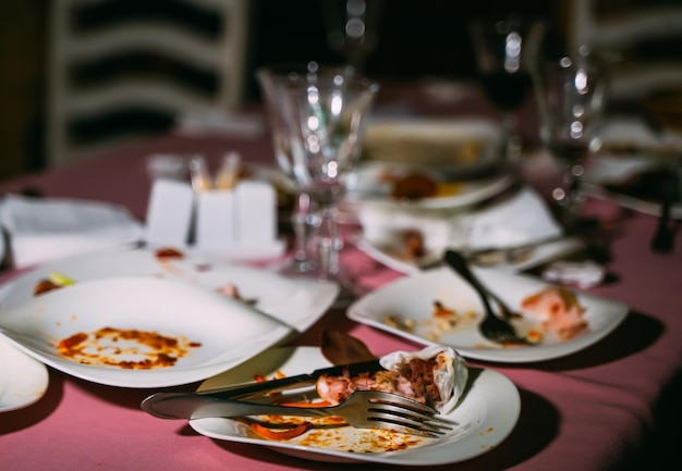 Remains of food in plates crumbs on the table after lunch or dinner Concept of the restaurant business