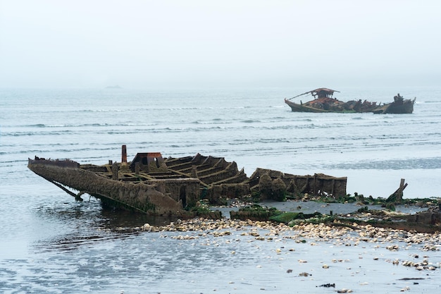 Remains of a wrecked ship on a foggy seashore