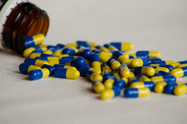 лекарственные средства в капсулах на белом фоне с синими и желтыми таблетками