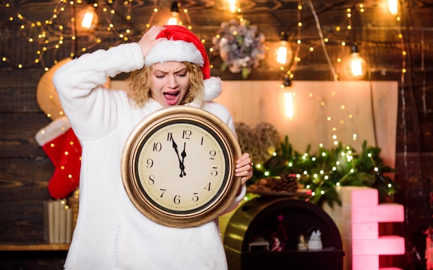 Remember these moments. Cheerful woman.. Time to celebrate. winter holidays. Its time for christmas. girl in red santa hat. Midnight. happy new year. christmas preparation. xmas mood. Woman wi clock.