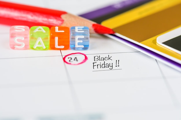 Напоминание Черная пятница Продажа в белом календаре с красной ручкой и кредитными картами