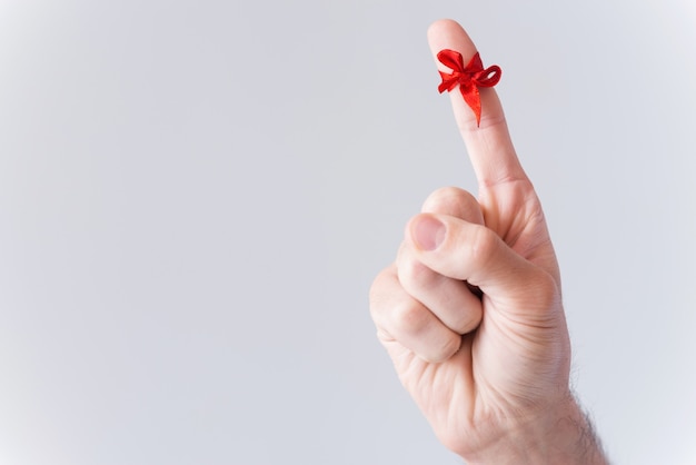 Reminder.  Close-up of male finger with tied with red ribbon and isolated on white