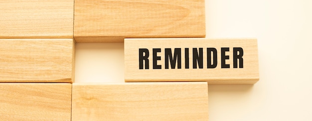 REMINDER text on a strip of wood lying on a white table.