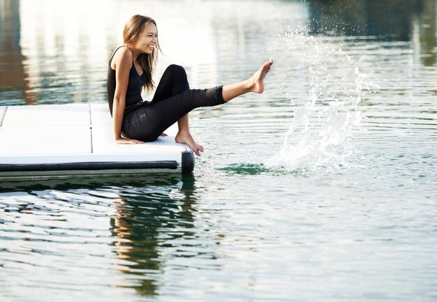 Reminiscing about her childhood years A gorgeous young woman playfully kicking up water at the harbour