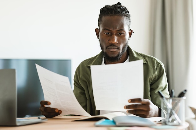 Remote career freelance job concept Focused black man working at home and looking through business documents