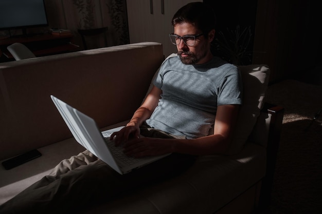Remote Job Man aan het werk op Laptop zittend op de Bank thuis