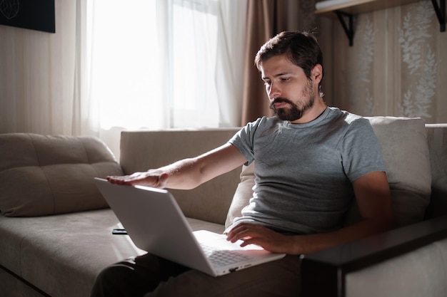 Remote Job Man aan het werk op Laptop zittend op de Bank thuis