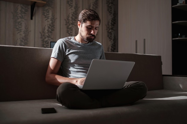 Remote Job Man Working On Laptop Sitting On Sofa At Home