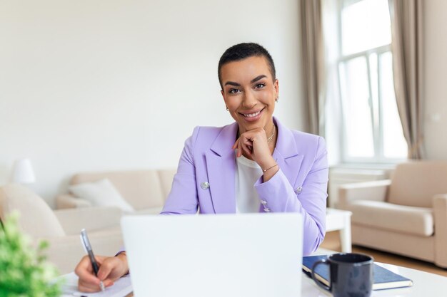 Tecnologia di lavoro a distanza e concetto di persone giovane donna d'affari nera sorridente felice con computer portatile e documenti che lavorano a casa in ufficio