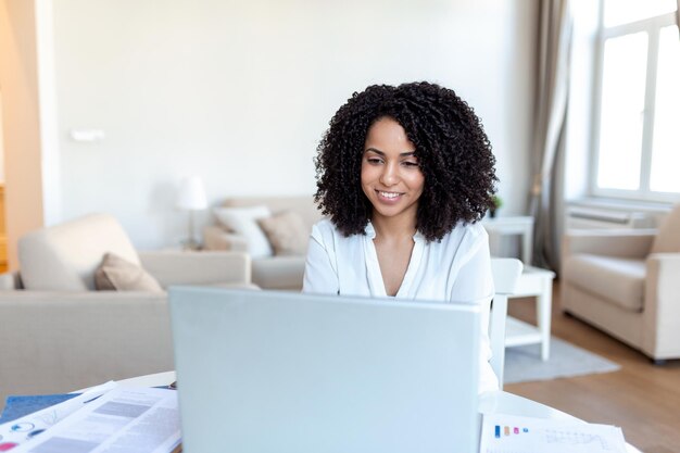 Remote job technology and people concept happy smiling young business woman with laptop computer and papers working at home office during the Covid19 health crisis