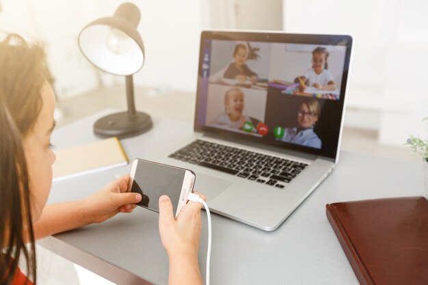 Lezioni a distanza. il bambino sorride felice e acquisisce conoscenza a distanza. la bambina studia l'apprendimento online da casa con il computer portatile. scuola in linea.