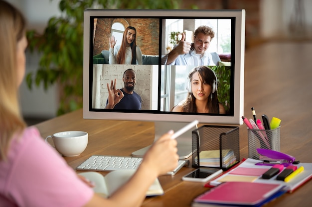 Remote meeting. Woman working from home during coronavirus or COVID-19 quarantine, remote office concept. Young boss, manager in front of monitor during online conference with colleagues and team.