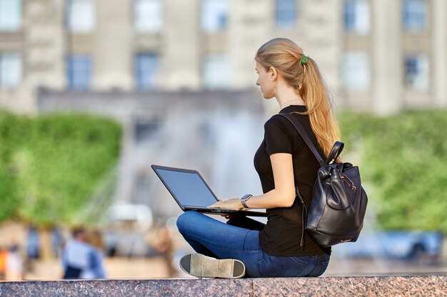 Remote work by woman with laptop in city garden