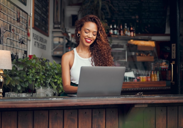 Remote work laptop and woman at restaurant typing blog article with satisfied and happy smile Freelance blogger girl working online and thinking of creative idea at casual cafe in Mexico