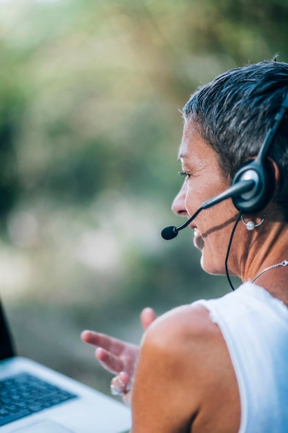 Foto lavoro a distanza donna di mezza età positiva che lavora a distanza indossando un auricolare che parla