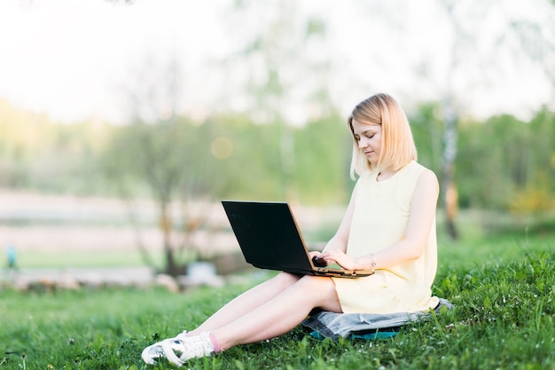 remote work young woman works with a laptop in a park in nature Selfisolation and internet work