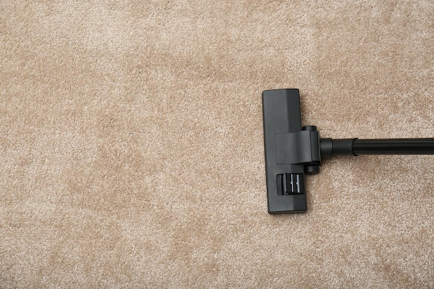 Removing dirt from carpet with vacuum cleaner indoors top view Space for text