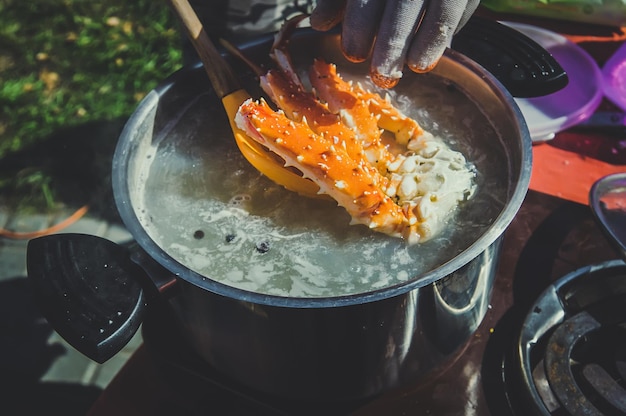 Removing large cooked crab from hot steaming pot