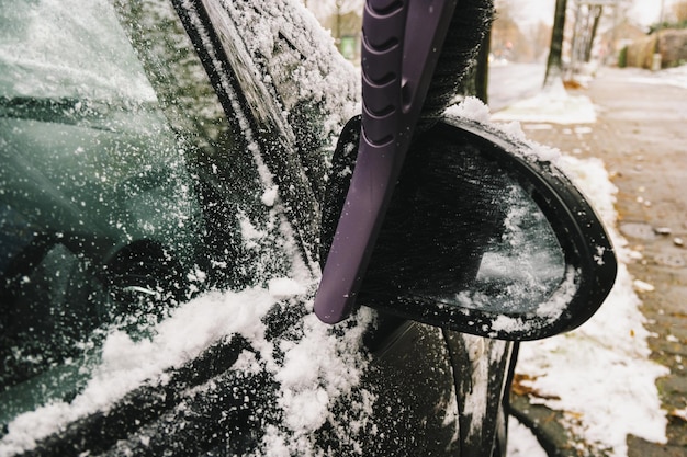 Rimuovere la neve dallo specchietto retrovisore di un'auto con una spazzola