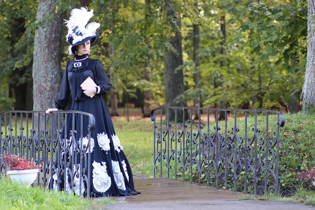 公園の橋の上の本を持つルネッサンスの女性