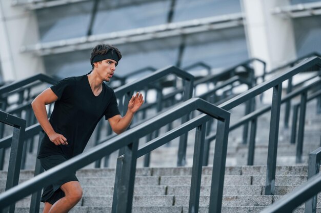 Rennen en springen Jonge man in sportieve kleding traint overdag buiten