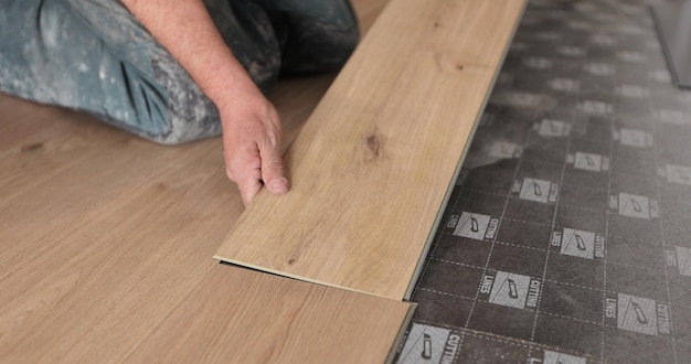 写真 木の床を設置する男性の改修工事の床材と人々のコンセプトのクローズアップ
