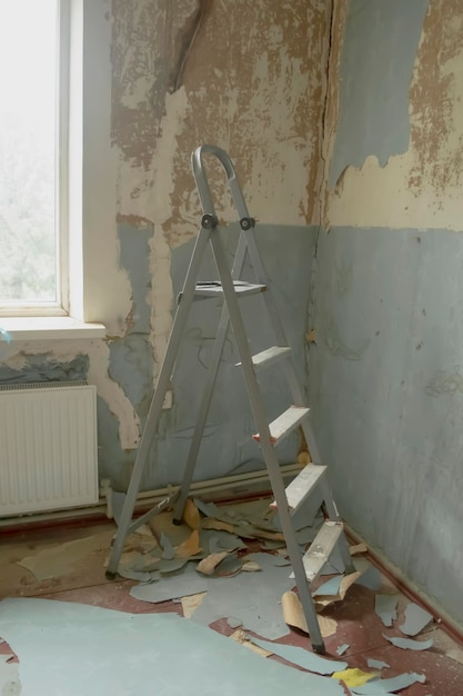 Renovation in the room among the tattered wallpaper there is a staircase stairs for renovation in a dirty room