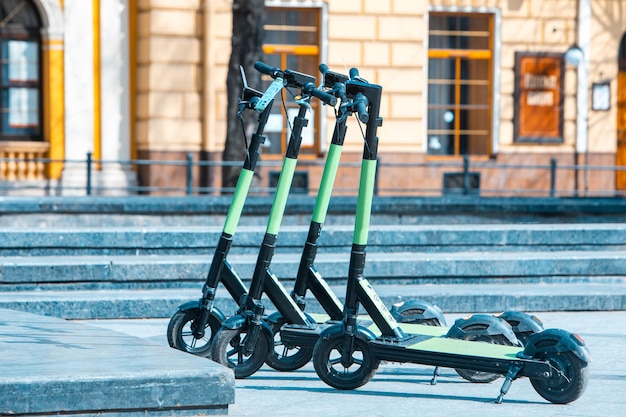 Rental electric kick scooter parked at city street copy space