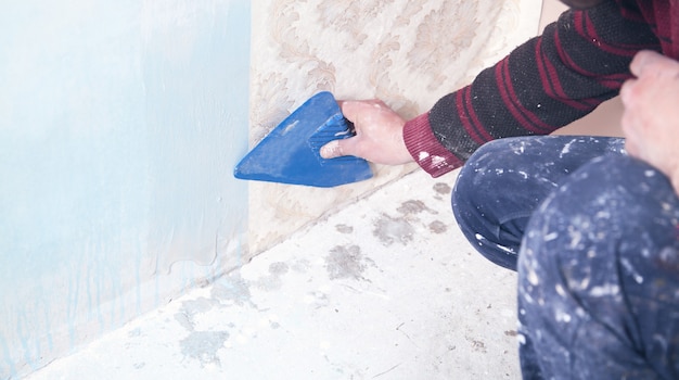 Repair the apartment. Worker glues the wallpaper to the wall.