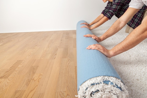 Repair, building and home concept - close up of human hands rolling carpet