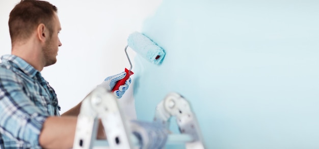 repair, building and home concept - close up of male in gloves holding painting roller