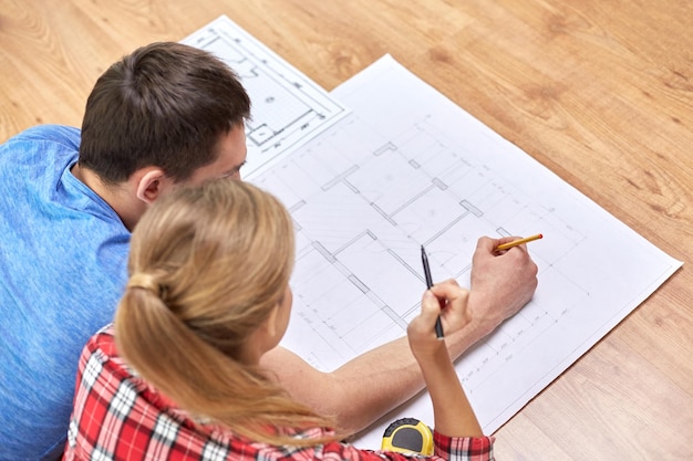 repair, building, renovation and people concept - close up of happy couple looking at blueprint at home